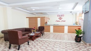 Un área de recepción con mostrador, un sofá de cuero marrón y una mesa de centro.