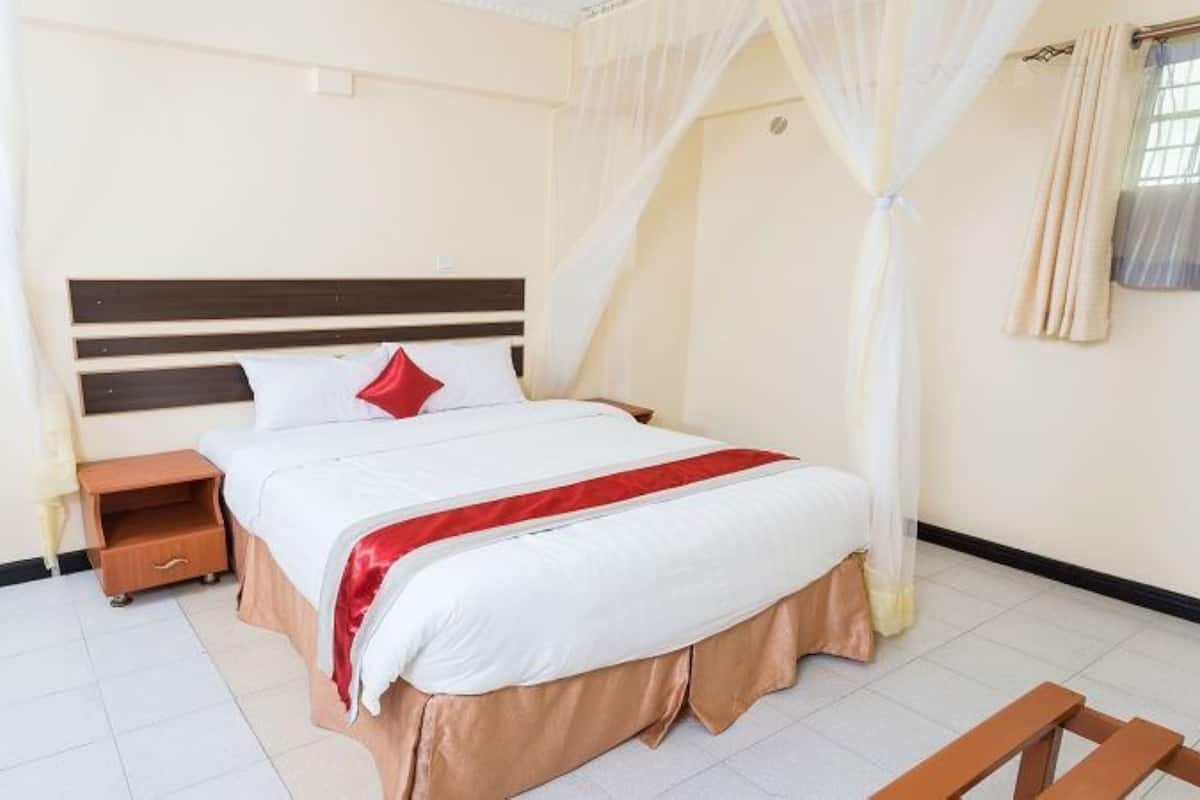 A bedroom with a bed, nightstand, and a wooden bench.