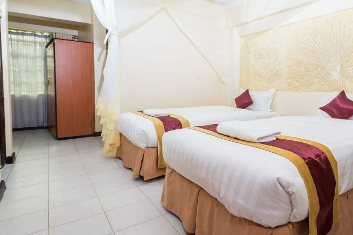A hotel room with two beds, a wardrobe, and a curtain.