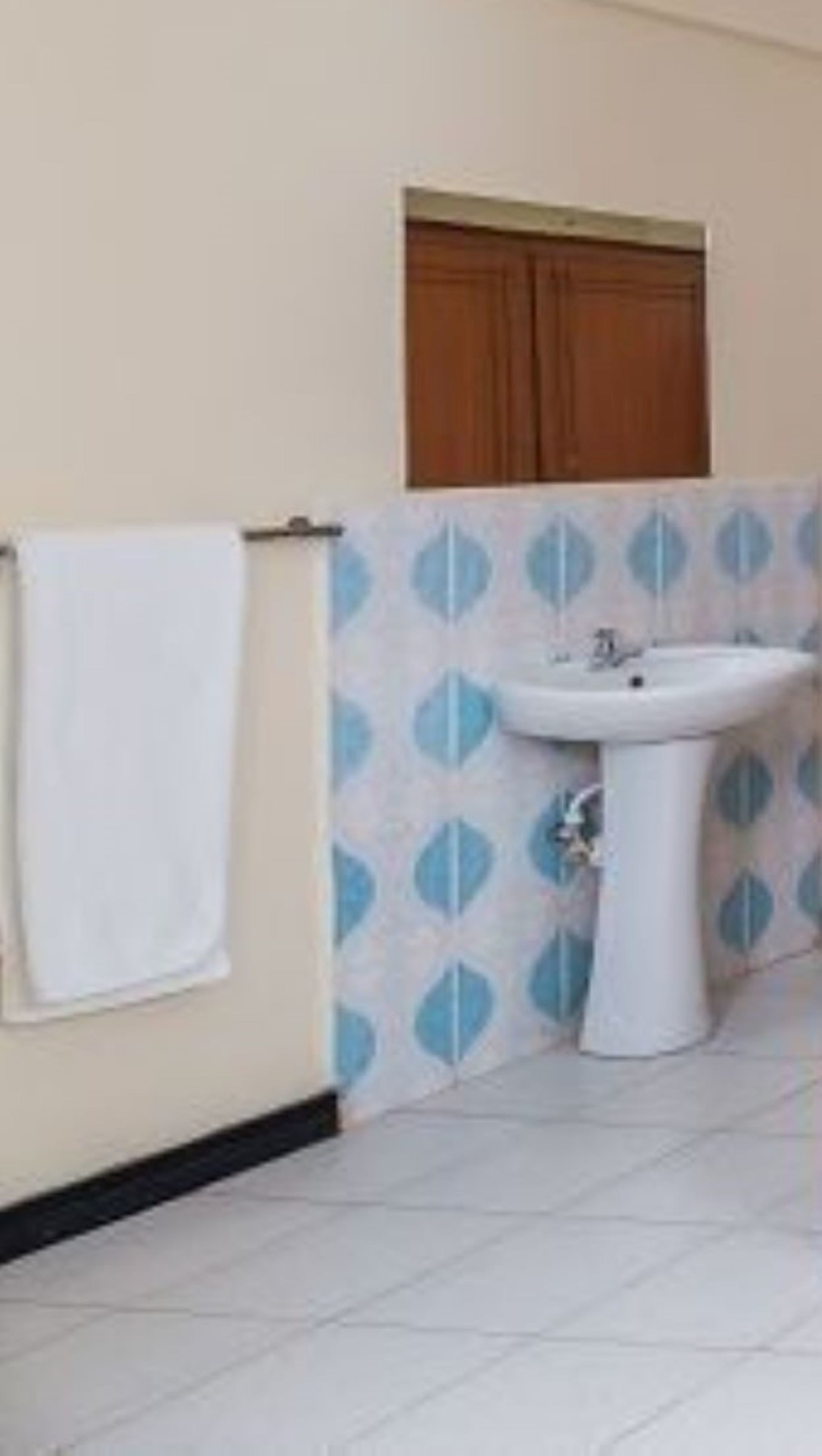 Un baño con un lavamanos blanco, una toalla colgada en la pared y baldosas estampadas.