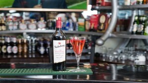 Una botella de vino Nedermark y un cóctel rojo sobre una barra con un tapete verde.