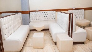 Una habitación de hotel moderna con un sofá modular, una mesita redonda y un otoman a juego.