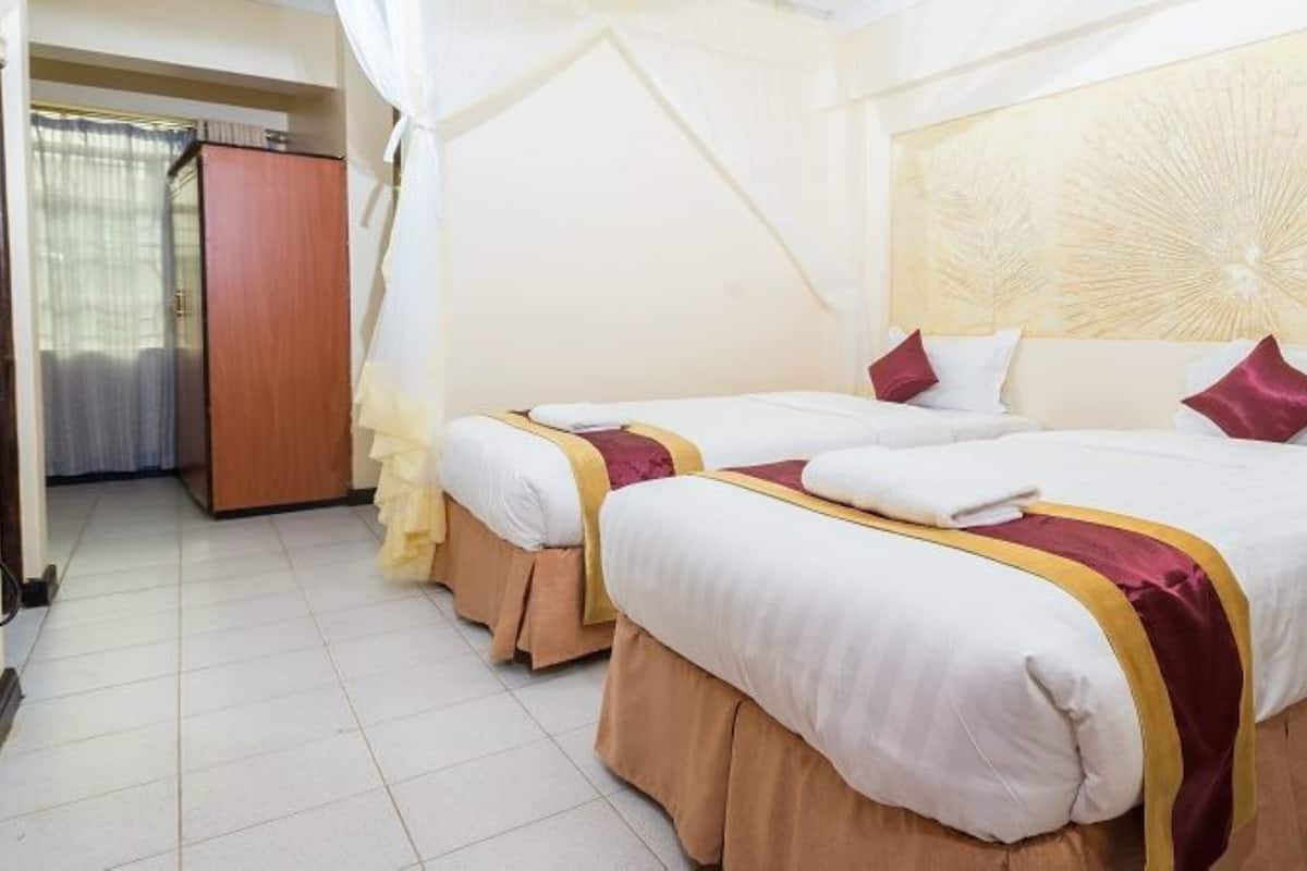 A hotel room with two beds, a wardrobe, and a curtain.