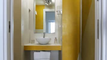 Un baño moderno con inodoro blanco, lavamanos con espejo y ducha con puerta de cristal.