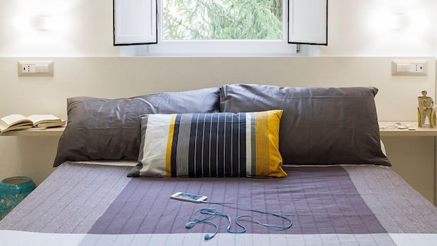 A bed with two pillows, a book, and earphones on a bedspread. - Il Vicoletto (Amalfi)