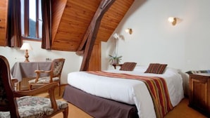 A bedroom with a large bed, wooden headboard, a chair, a table, and a lamp. - Logis Le Relais Chenonceaux (Chenonceaux)