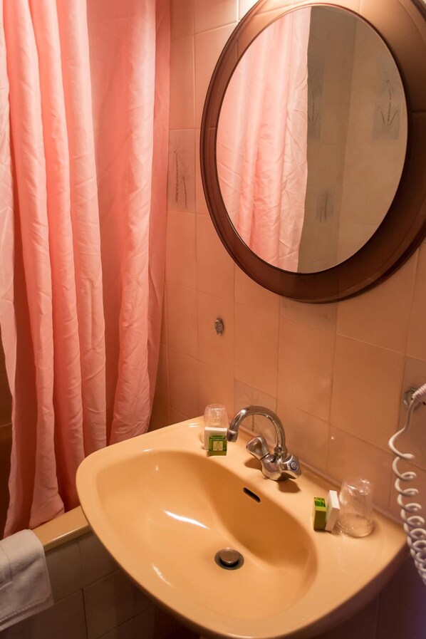 A bathroom with a beige sink, a round mirror, and a pink shower curtain. - Logis Le Relais Chenonceaux (Chenonceaux)