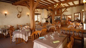 A restaurant with wooden beams, tables set for dining, and a chandelier. - Logis Le Relais Chenonceaux (Chenonceaux)