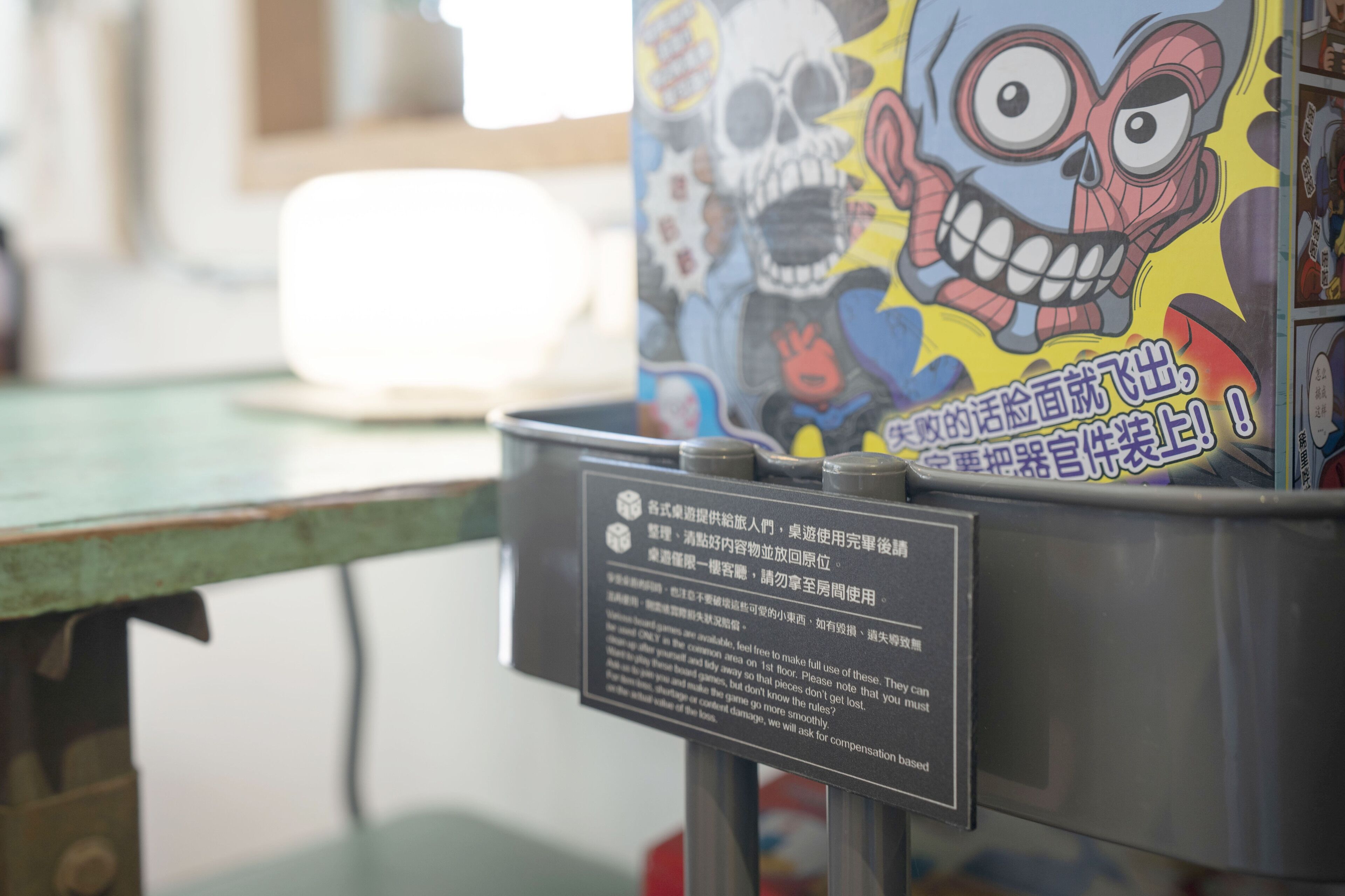 A metal container with a skull and cartoon character design, and a sign with text in a foreign language.