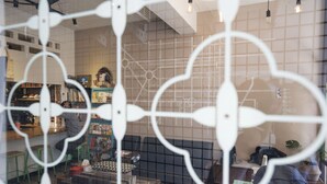 A cafe interior with a modern design, featuring a bar area, seating arrangements, and a visible menu board. - Lento Hostel (Tainan)