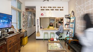 A cozy living room with a television, wooden furniture, and a green sofa. - Lento Hostel (Tainan)