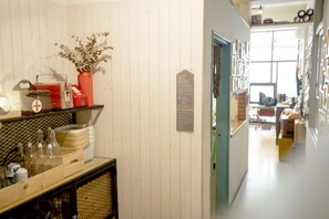 A hallway with a wooden wall, a door with a sign, and a counter with various items.