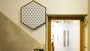 A room with a patterned wall, a door with a circular mirror, and a light switch. - Lento Hostel (Tainan)