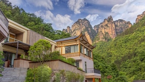 A modern building with a traditional architectural style, surrounded by lush greenery and mountains. - Pandora Vista Retreat  (Zhangjiajie)