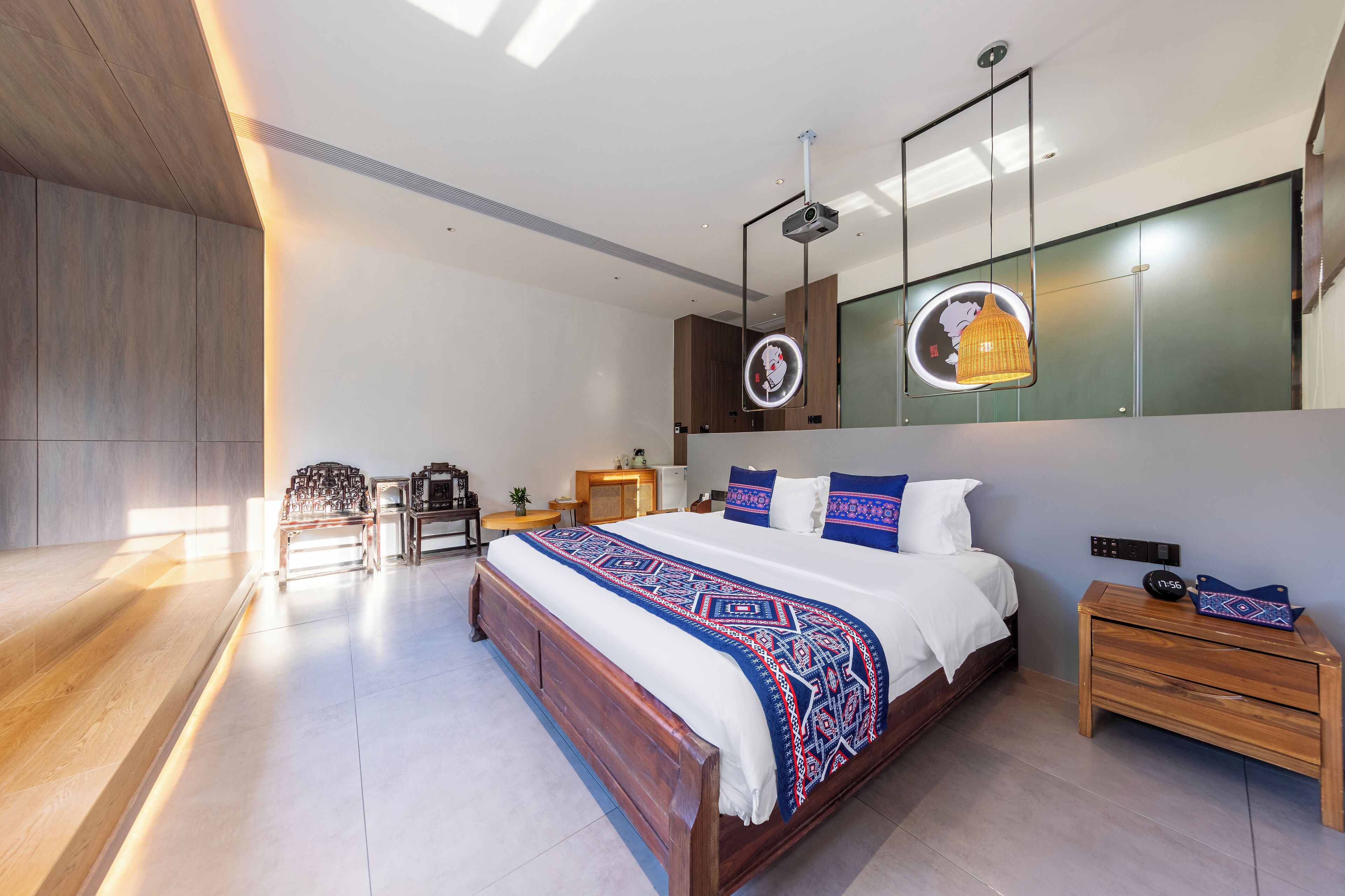 Un dormitorio moderno con una cama grande, mesitas de noche, un espejo y un proyector de techo.