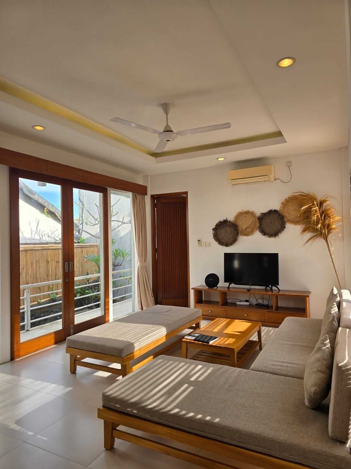 Un salon moderne avec un canapé, une table basse, un téléviseur et un ventilateur de plafond.