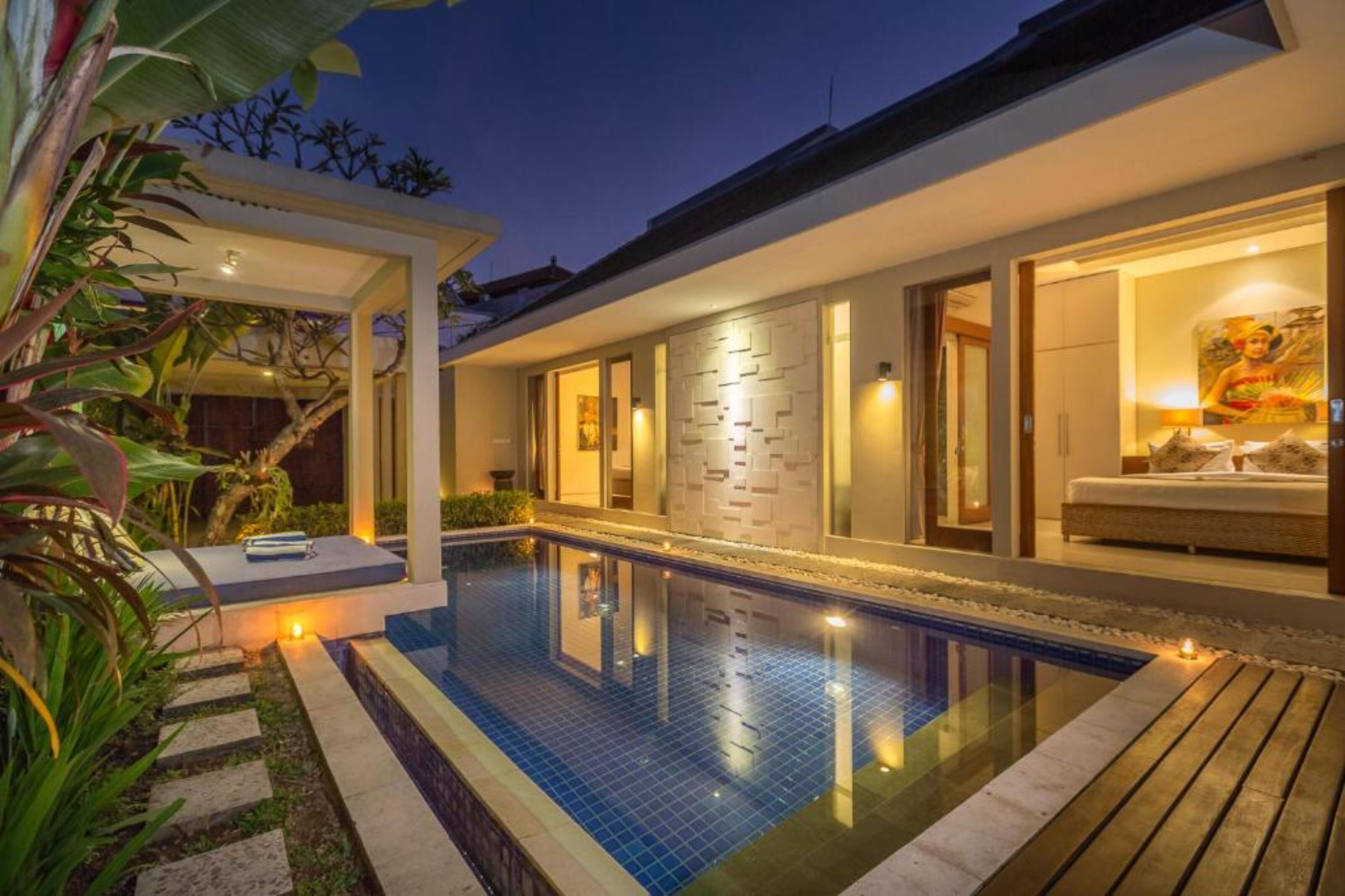 A modern house with a swimming pool, a covered patio, and a well-lit interior.