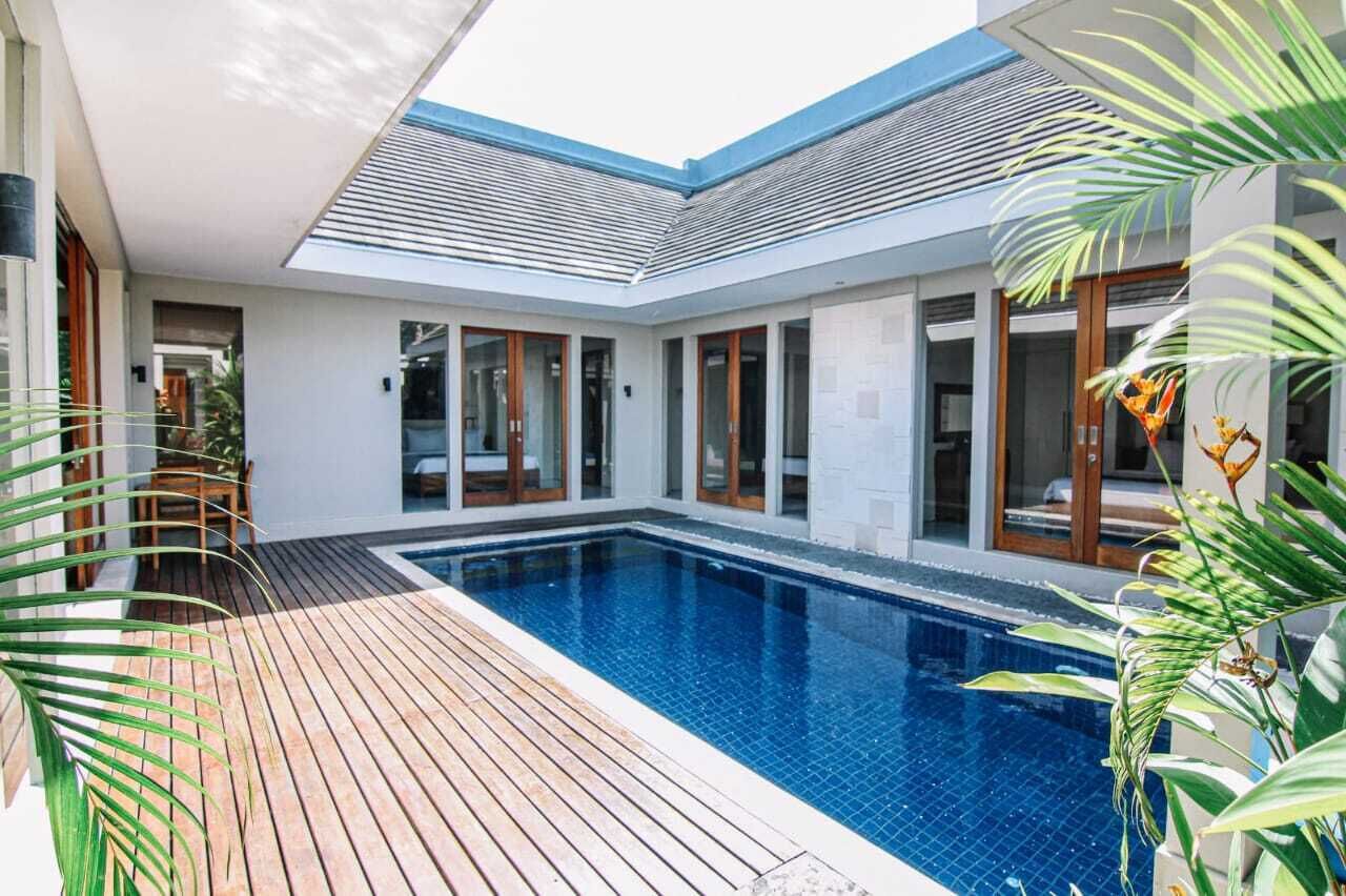 Ein modernes Haus mit Swimmingpool, Holzterrasse und großen Fenstern.