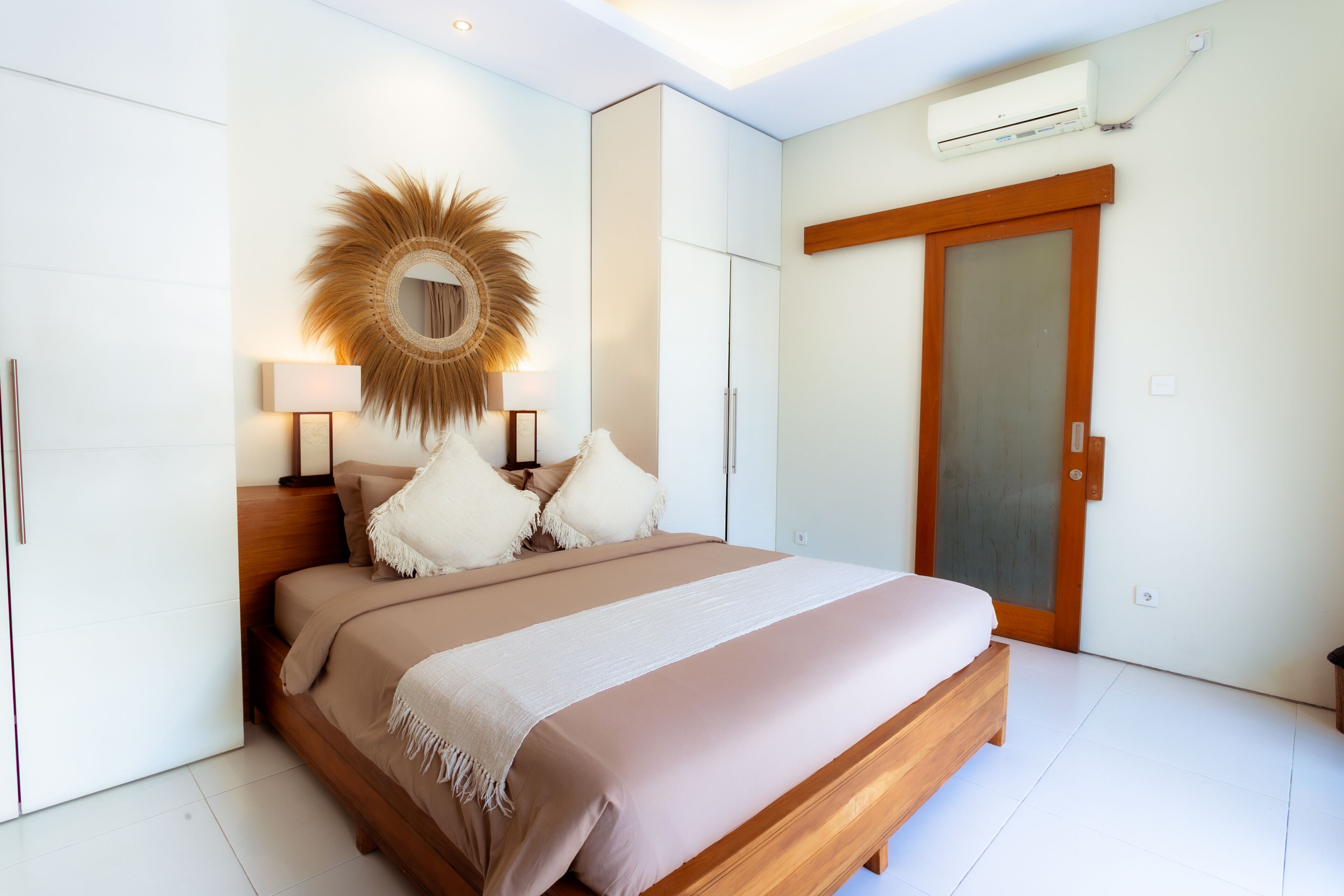 A modern bedroom with a large bed, a decorative mirror, and a wardrobe.