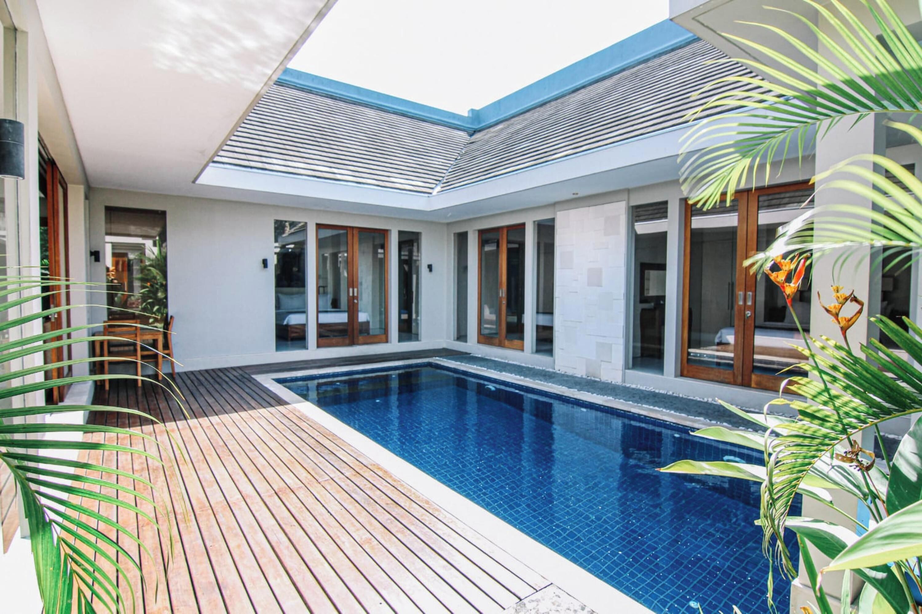 Une maison moderne dotée d’une piscine, d’une terrasse en bois et de grandes fenêtres.