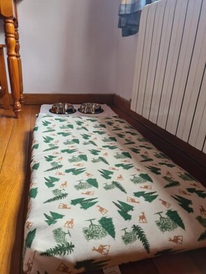 A corner of a room with a patterned tablecloth, two metal bowls, and a wooden chair. - Hotel Rural La Posada El Sestil (Vega de Liebana)