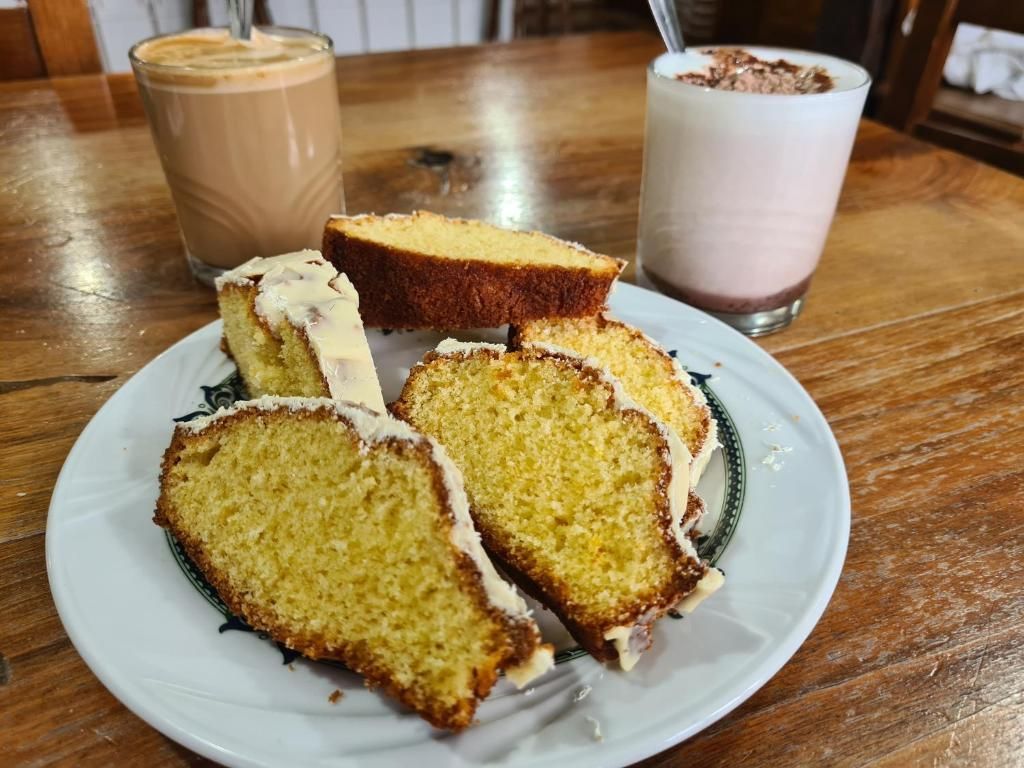 A plate with slices of cake and two glasses of beverages on a wooden table.