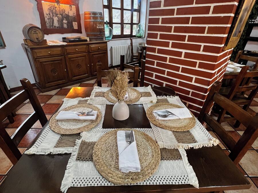 A dining area with a brick wall, wooden furniture, and a table set for four.