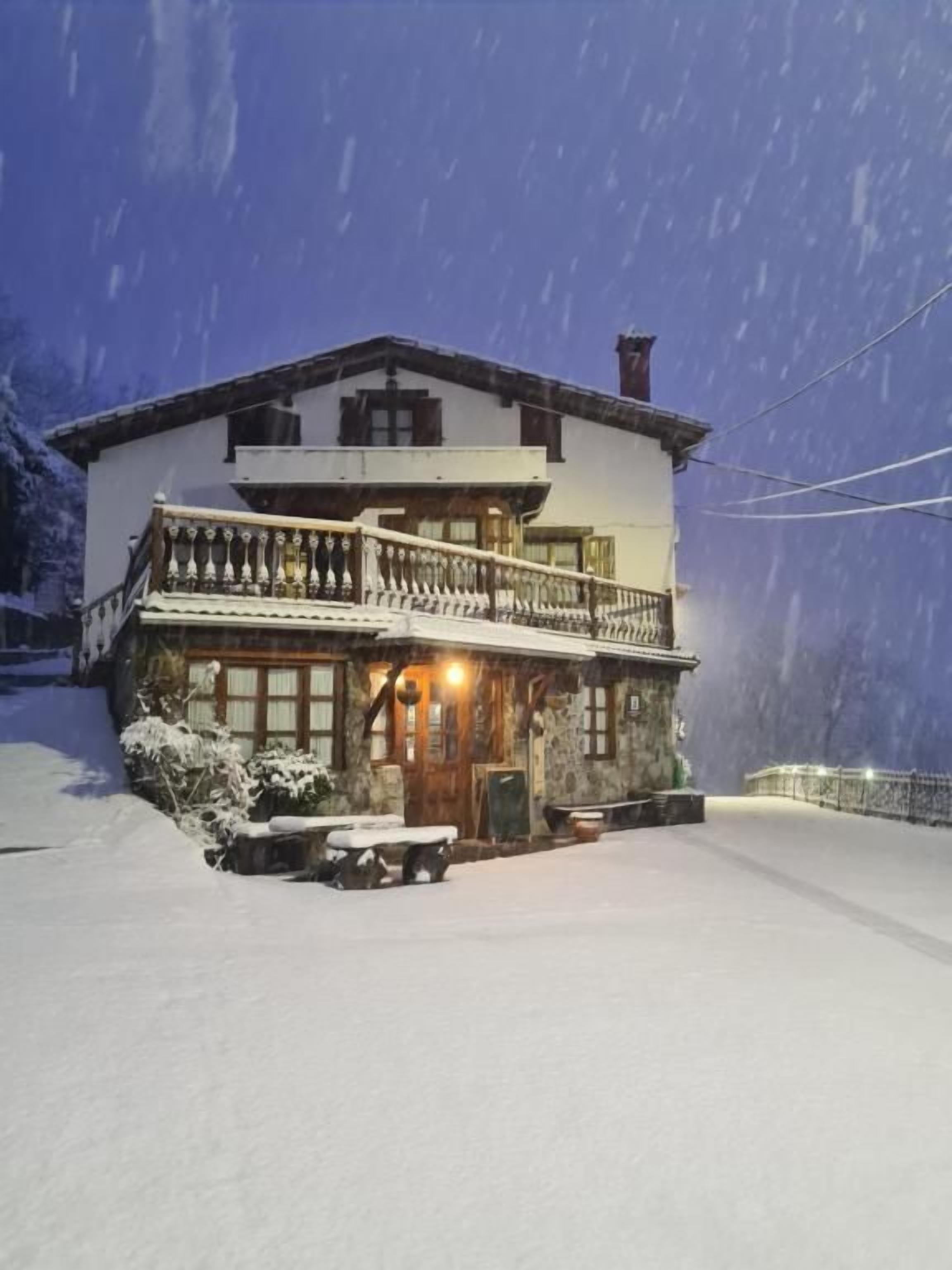Een gebouw met twee verdiepingen en een balkon, met een besneeuwde omgeving en een duidelijke ingang.