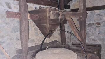 Un moulin en pierre doté d’une structure en bois et d’une forme conique.