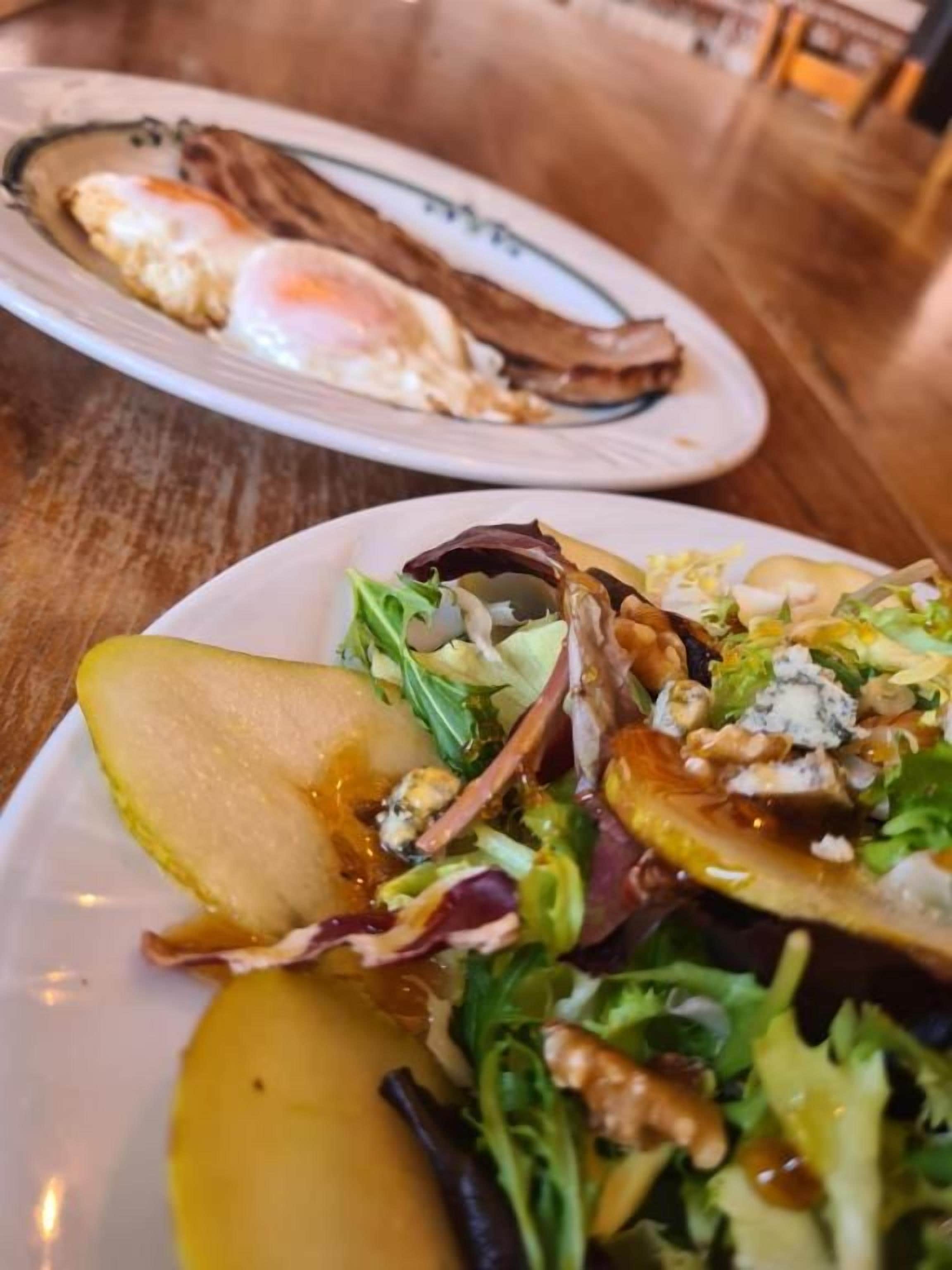A dining table with plates of food, including a salad and a plate with eggs and bacon.