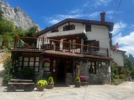 Un edificio de dos pisos con fachada de piedra, un balcón con barandilla decorativa y un letrero que indica estacionamiento privado.
