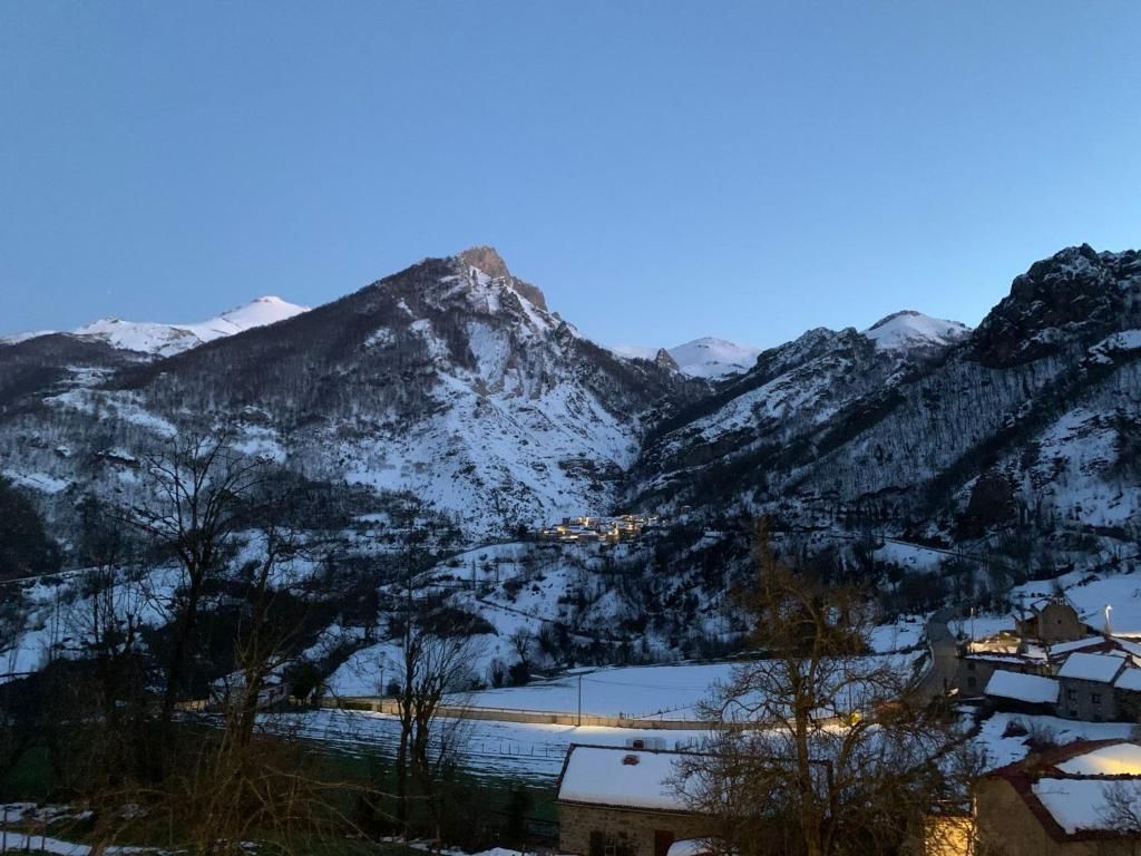 Paisatge de muntanya amb cims nevats i un poble al primer pla.