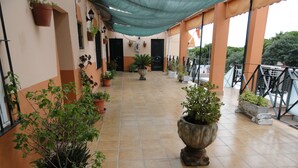 A covered corridor with potted plants, tiled flooring, and a view of the outside. - Hostal La Campa (Chiclana de la Frontera)