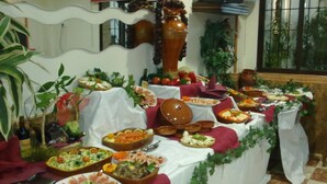 A buffet table with various dishes and a decorative vase. - Hostal La Campa (Chiclana de la Frontera)