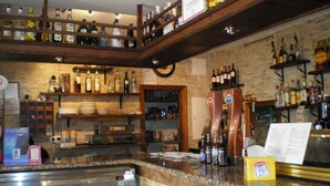 A bar area with shelves of liquor bottles, a coffee machine, and a menu stand. - Hostal La Campa (Chiclana de la Frontera)