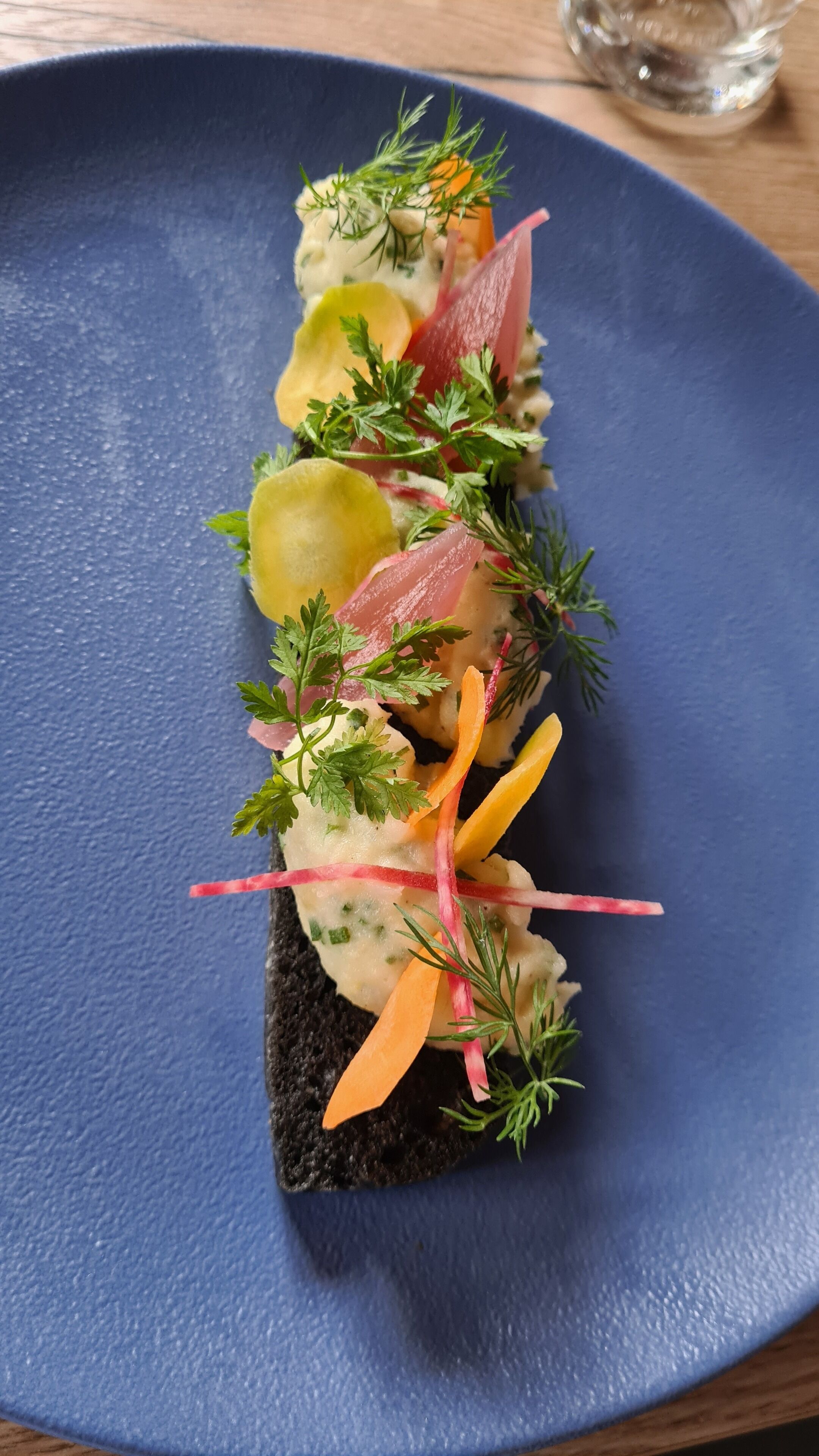 A dish with various ingredients on a dark blue plate.