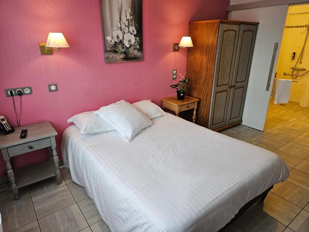 A hotel room with a bed, bedside lamps, a wardrobe, a nightstand with a phone, and a painting on the wall.