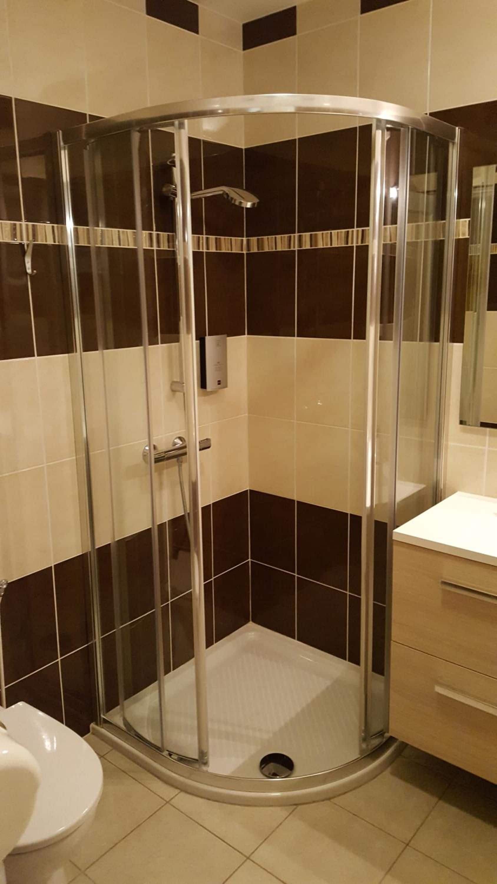 A corner shower enclosure with a glass door, a toilet, and a vanity with drawers.
