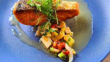 Ein blauer Teller mit Lachs und gemischtem Gemüse.
