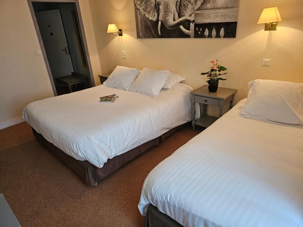 A hotel room with two beds, a door, a wall-mounted artwork, and a nightstand with a lamp.
