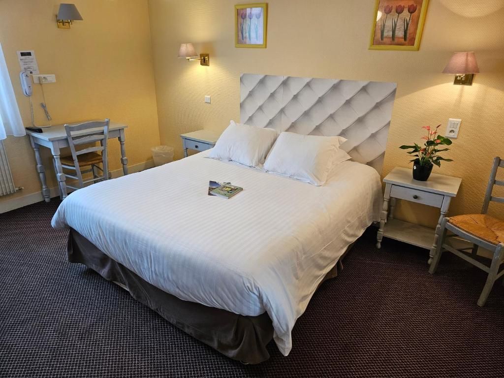 A hotel room with a large bed, bedside tables, a desk, and a chair.