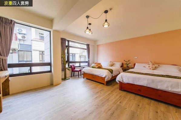 Una habitación con dos camas, un escritorio y una silla. Hay una ventana con cortinas y vistas a edificios.