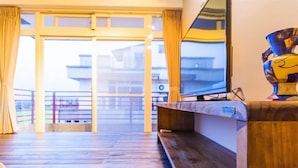 A hotel lobby with a wooden reception desk, a large window with curtains, and a view of the outside balcony. - Happy Snails (Wujie)