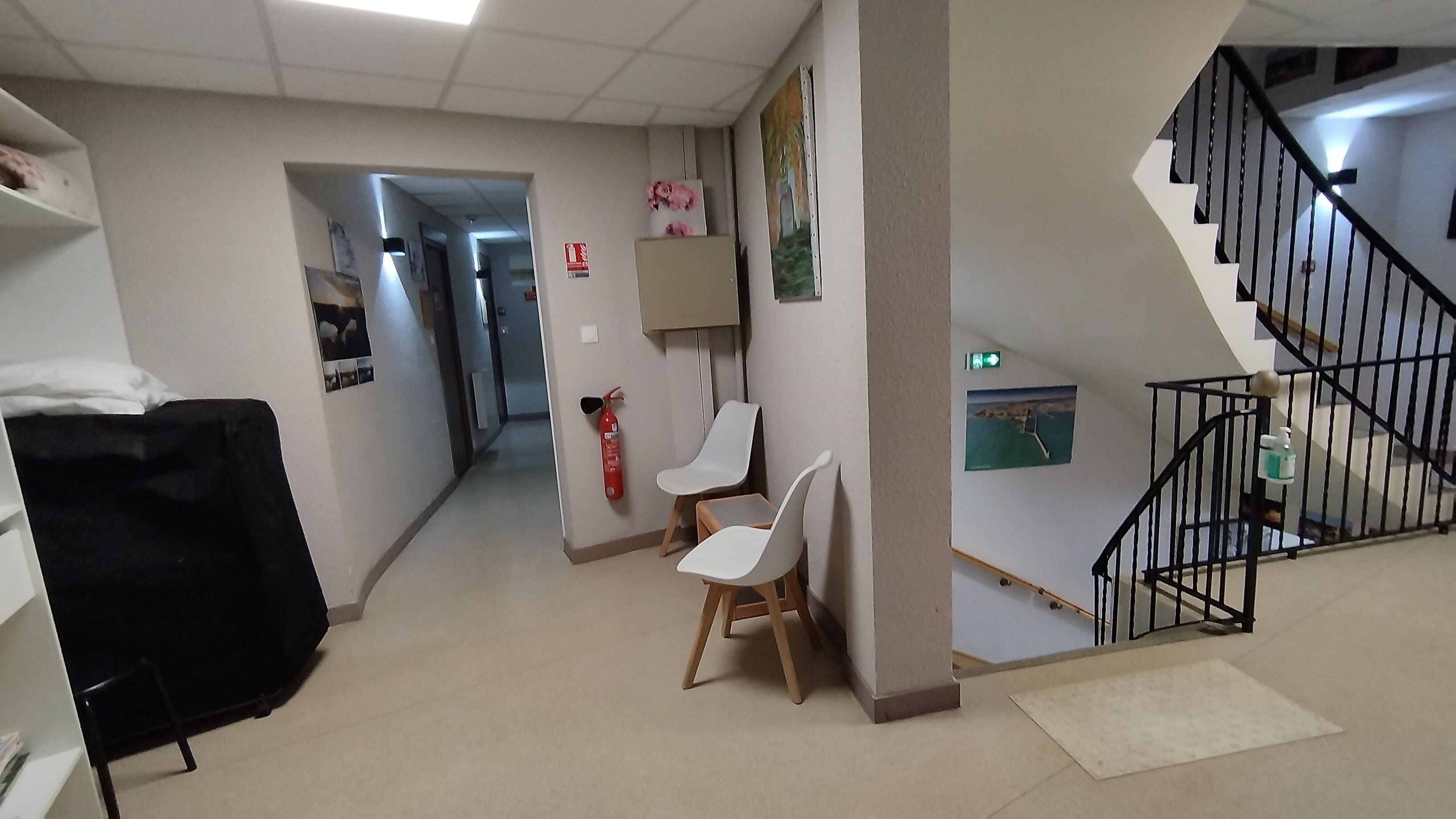 Un pasillo de hotel con una escalera, un extintor y un pequeño espacio de descanso.