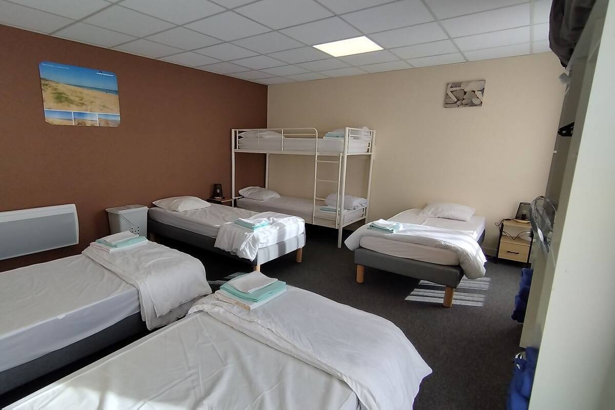 A hotel room with bunk beds, a bedside table, a lamp, and a wall-mounted picture.