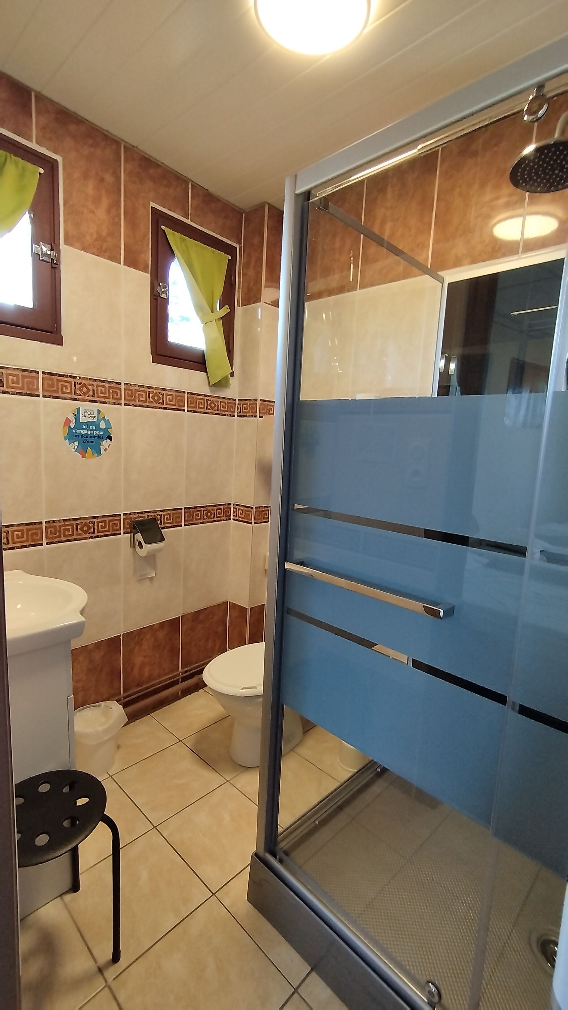 A bathroom with a shower, toilet, sink, and a towel rack.
