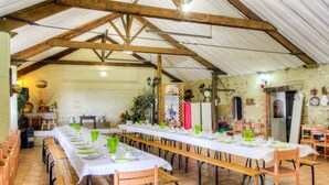 Una larga mesa de comedor dispuesta para una comida en un comedor rústico con vigas de madera y paredes de ladrillo.