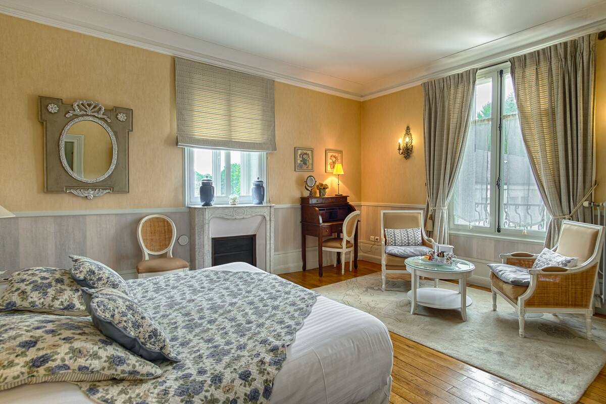 A well-appointed bedroom with a large bed, a desk, a chair, and a small table.