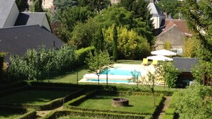 A pool surrounded by well-manicured hedges, with a view of historic buildings in the background. - Manoir Du Parc - Adults Only (Amboise)