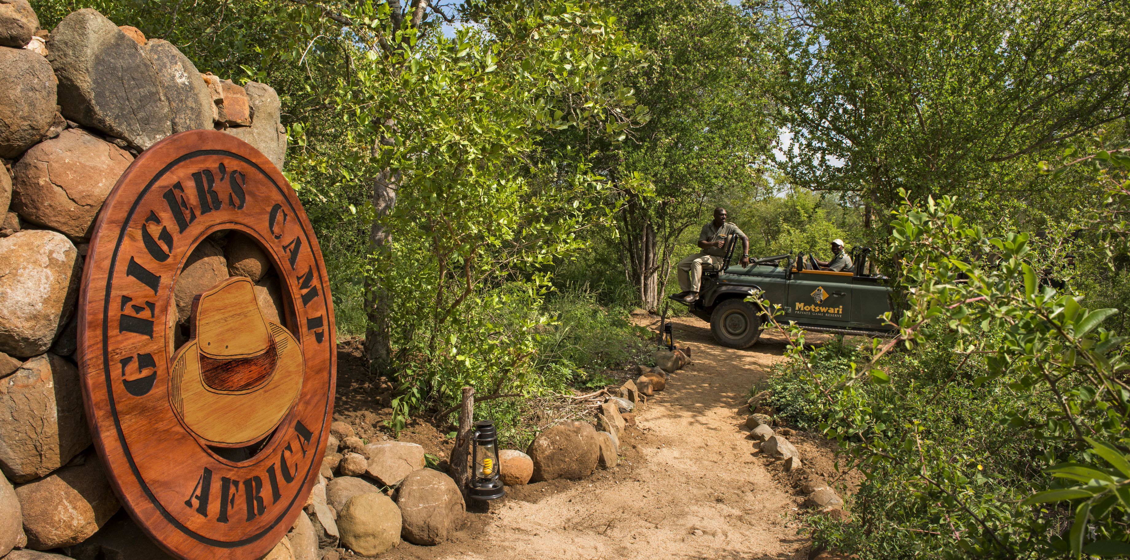 A wooden sign with the text "GEIGER'S CAMP AFRICA" and a tent.